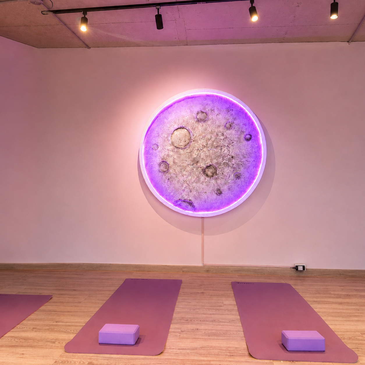 Sala de Peachy Studio con tapetes de yoga y arte lunar iluminado en la pared